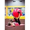 Group of people in a pilates class at the gym - young woman with gymball at fitness training (shallow DOF, color toned image)