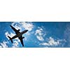 Dark silhouette of an airplane flying over the blue skies