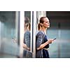 Portrait of a sleek young woman calling on a smartphone and using her laptop in a an
urban/city context (shallow DOF; color toned image)