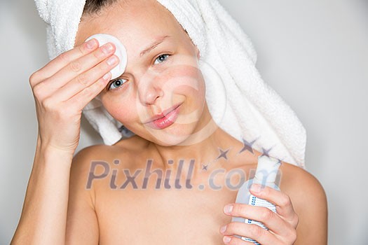 Beautiful brunette woman removing makeup from her face