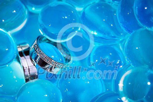 Wedding rings amid blue balls Wedding rings amid blue balls