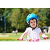 Cute smiling little girl with bicycle and helmet on road in the park