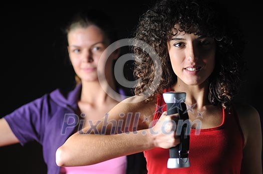 two girls working out with dumbbell in fitness club two girls working out with dumbbell in fitness club