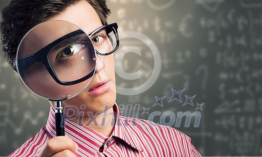 Young man scientist looking in magnifying glass