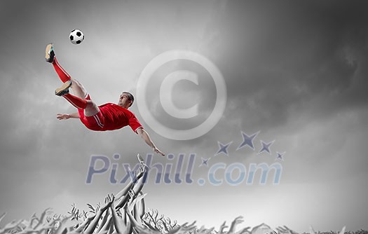 Football player in jump kicking the ball supported by fans Football player in jump kicking the ball supported by fans