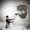 Young businesswoman crashing stone shield with hammer