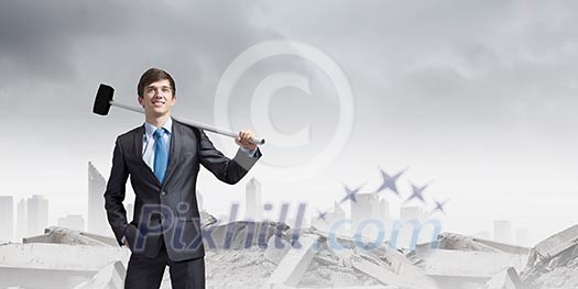 Young determined businessman breaking wall with hammer