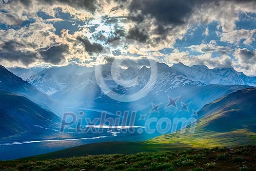 HImalayan valley landscape with Himalayas mountains. Sun rays come through clouds. Himachal Pradesh, India