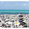 Zen meditation spa relaxation background -  balanced stones stack with frangipani plumeria flower close up on sea beach