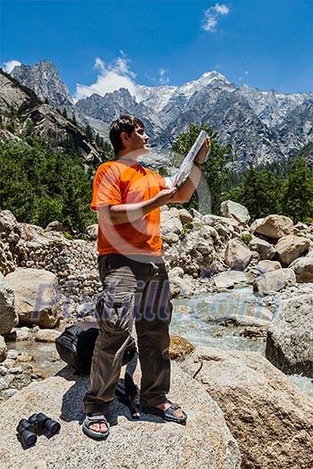 Hiker trekker studying map route on trek in Himalayas mountains. Himachal Pradesh,India Hiker trekker studying map route on trek in Himalayas mountains. Himachal Pradesh,India
