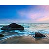 Tropical beach vacation background - waves and rocks on beach of sunset