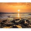 Tropical beach vacation background - waves and rocks on beach on sunset with beautiful cloudscape