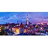 Panorama of aerial view of Tallinn Medieval Old Town with St. Olaf's Church and Tallinn City Wall illuminated in evening, Estonia