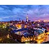 Aerial view of Tallinn Medieval Old Town with St. Olaf's Church and Tallinn City Wall illuminated in evening with dramatic cloudscape, Estonia