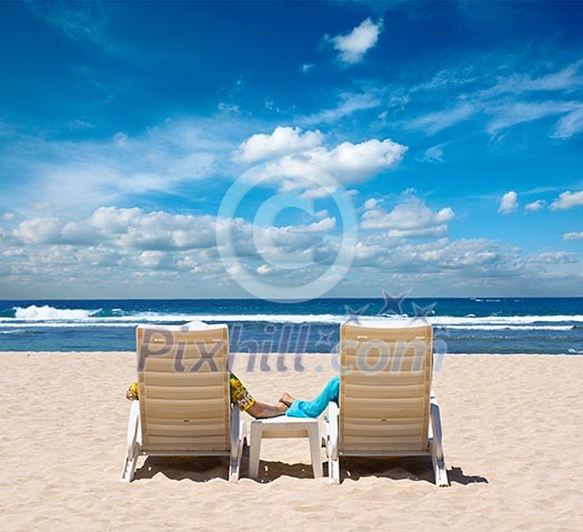 Couple in beach chairs holding hands near ocean