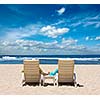 Couple in beach chairs holding hands near ocean