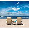 Couple in beach chairs holding hands near ocean