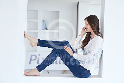 happy young woman using cellphone at home and relaxing happy young woman using cellphone at home and relaxing