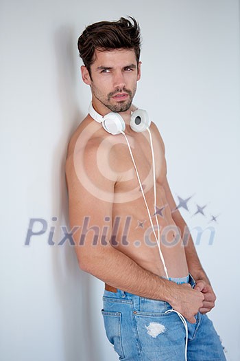 handsome young man listening music on headphones at modern home over white wall and standing on hands handsome young man listening music on headphones at modern home over white wall and standing on hands
