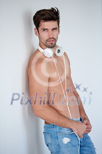 handsome young man listening music on headphones at modern home over  white wall and standing on hands