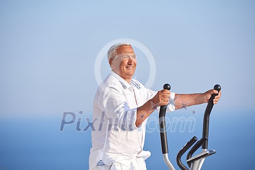 healthy senior man working out on gym treadmill machine at modern home terace with ocean view