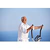 healthy senior man working out on gym treadmill machine at modern home terace with ocean view