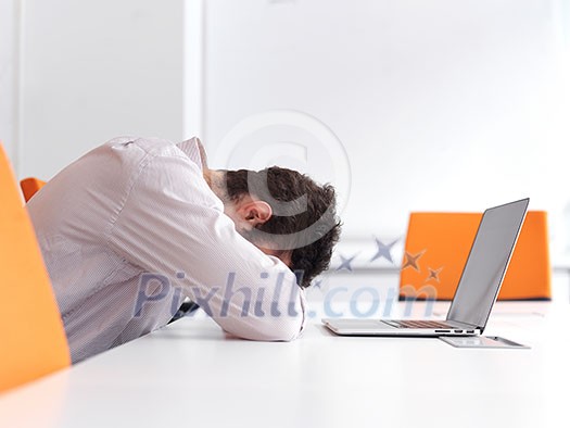 Frustrated young business man have stress problems. Sitting alone at office meeting room and working on laptop compute. Frustrated young business man have stress problems. Sitting alone at office meeting room and working on laptop compute.