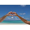 romantic couple make heart shape symbol of love with arms on sunny tropical beach and sea in background