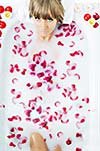 woman beauty spa and wellness treathment with red flower petals in bath with milk 