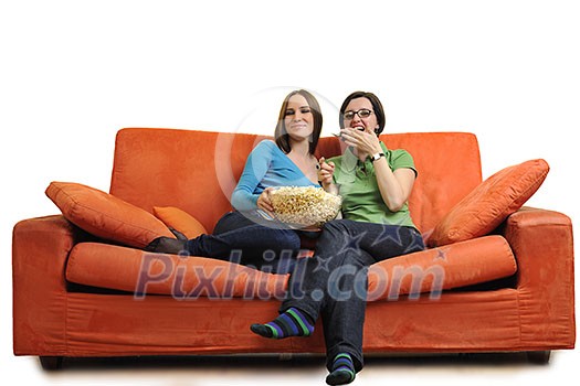 female friends eating popcorn and watching tv at home on orange sofa isolated on white