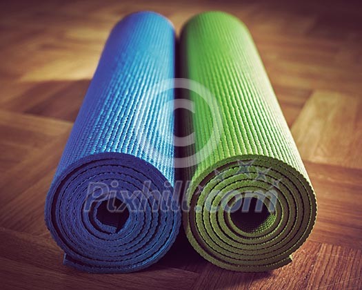Vintage retro effect filtered hipster style image of Yoga mats on wooden floor Vintage retro effect filtered hipster style image of Yoga mats on wooden floor