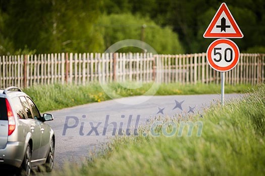 Car on a country road with limited speed and crossroad sign Car on a country road with limited speed and crossroad sign