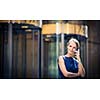 Pretty, young businesswoman talking on the phone in front of a modern building in Manhattan (shallow DOF; color toned image)