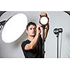 Young, pro photographer setting lights in his well equiped studio before a photo shoot (color toned image; shallow DOF)
