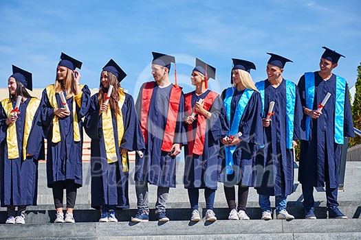 young graduates students group standing in front of university building on graduation day young graduates students group standing in front of university building on graduation day