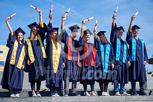 young graduates students group standing in front of university building on graduation day young graduates students group standing in front of university building on graduation day