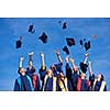high school students graduates tossing up hats over blue sky.