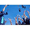 high school students graduates tossing up hats over blue sky.