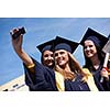 Capturing a happy moment.Students group  college graduates in graduation gowns  and making selfie photo