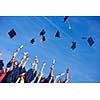 high school students graduates tossing up hats over blue sky.