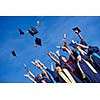 high school students graduates tossing up hats over blue sky.