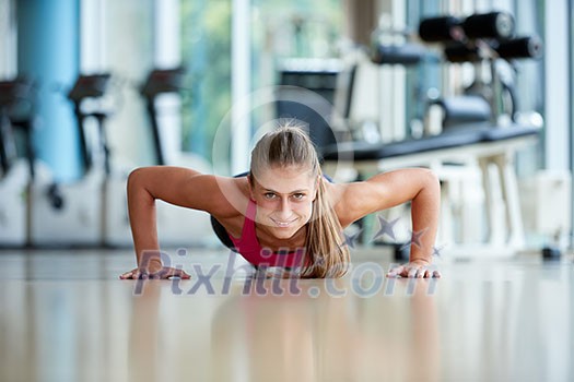 Gorgeous blonde woman warming up and doing some push ups a the gym
