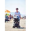 happy young mother walking on beach and push baby carriage