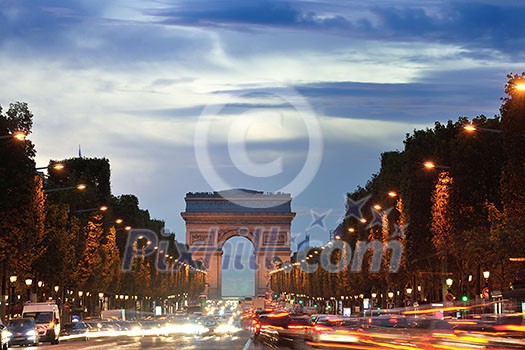 Beautiful night view with car traffic and rush at eavning of the Arc de Triomphe, Paris, France.