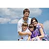 happy young family with their kids have fun and relax outdoors in nature with blue sky in background