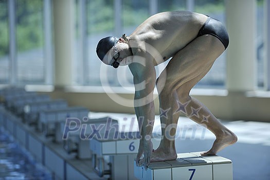 young swimmer on swim start at swimming pool ready for jump race and win young swimmer on swim start at swimming pool ready for jump race and win