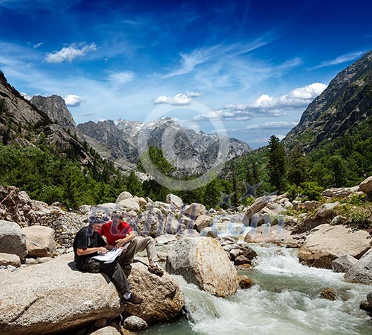 Hiker trekkers read a trekking map on trek in Himalayas mountains. Himachal Pradesh,India