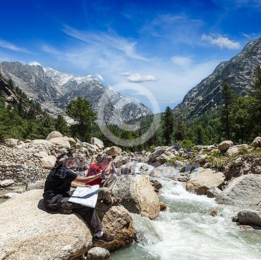 Hiker trekkers read a trekking map on trek in Himalayas mountains. Himachal Pradesh,India