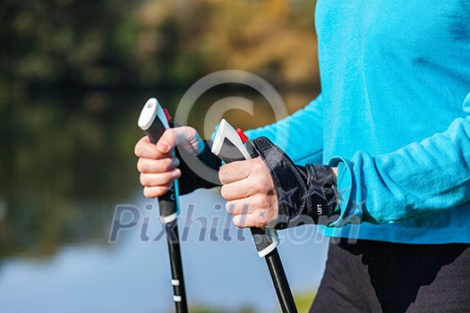 Nordic walking exercise adventure hiking concept - closeup of woman's hand holding nordic walking poles