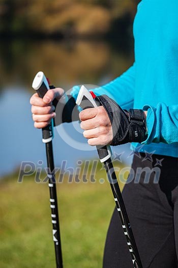 Nordic walking exercise adventure hiking concept - closeup of woman's hand holding nordic walking poles Nordic walking exercise adventure hiking concept - closeup of woman's hand holding nordic walking poles